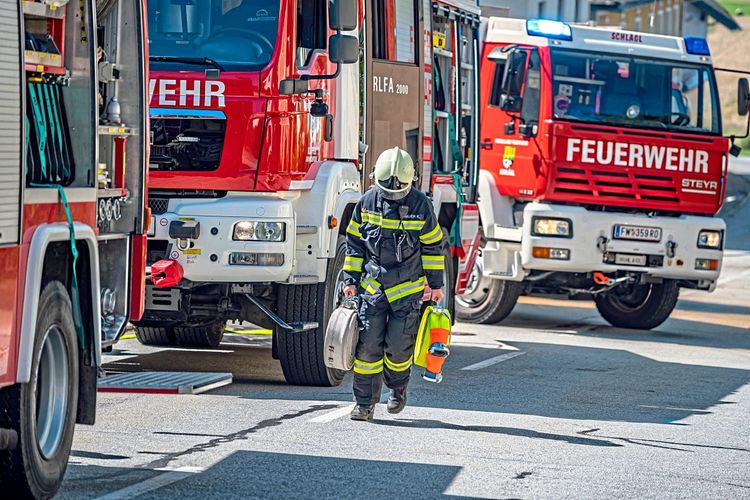 Feuerwehrmann neben drei Löschfahrzeugen