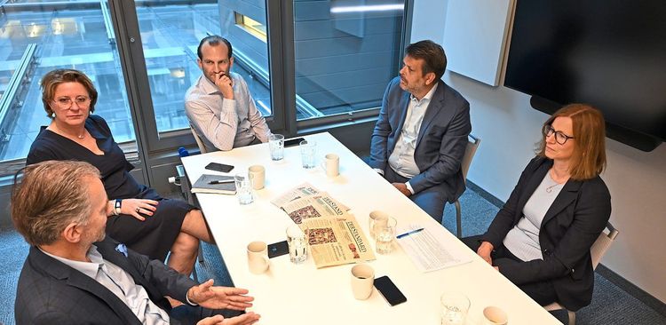 Fünf Unternehmensvertreter:innen sitzen an einem Tisch zur Diskussion