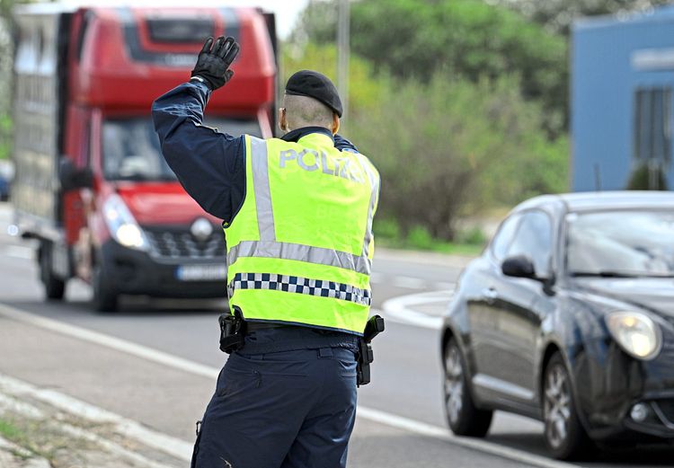 Ein Polizist stoppt Fahrzeuge an der Grenze.