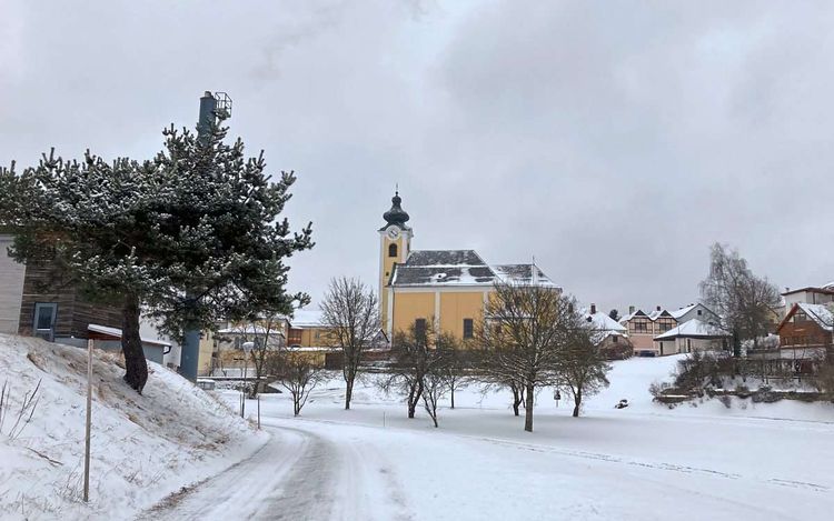 Die spätbarocke, gelb getünchte Pfarrkirche mit Zwiebelturm im verschneiten Arbesbach