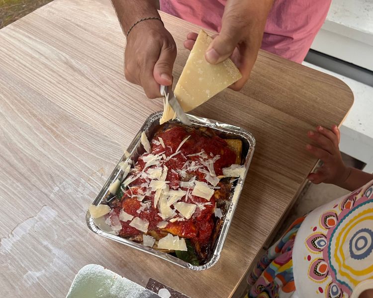 Angelo reibt den Käse auf die Parmigiana