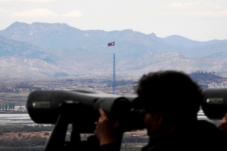 Ein Beobachter blickt durch ein Fernglas vom Dora-Observatorium in Paju, Südkorea, auf eine nordkoreanische Flagge, die auf einem 160 Meter hohen Turm im nordkoreanischen Propagandadorf Gijungdong weht. Im Hintergrund sind Berge zu sehen.