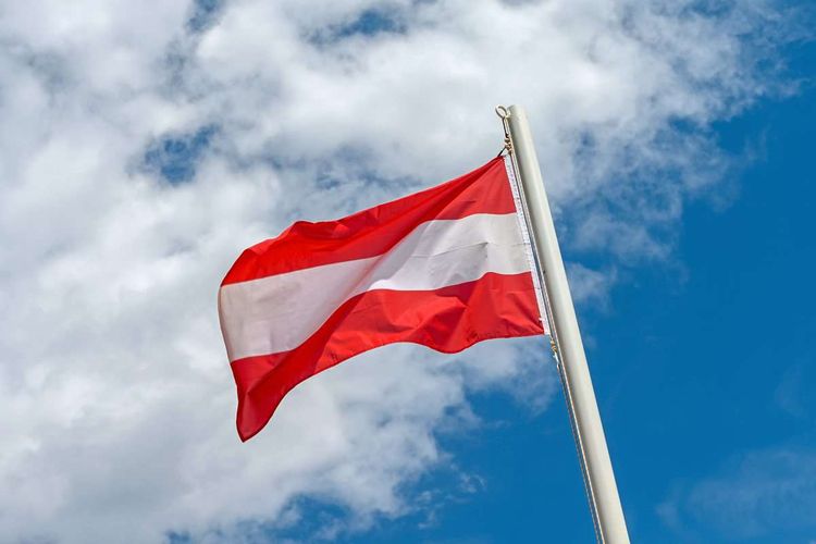 Österreich-Flagge weht in der Luft an einem wolkigen, aber sonnigen Tag