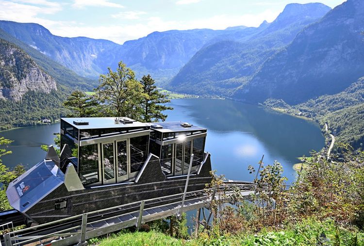 Eine moderne Standseilbahnkabine nahe der Bergstation in Hallstatt, oberhalb des Hallstätter Sees, umgeben von malerischer Berglandschaft und üppigem Grün.
