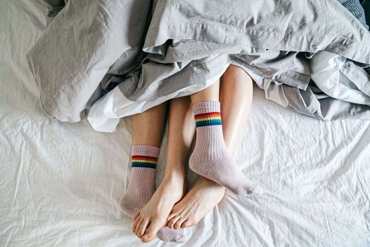 Füße schauen unter einer Bettdecke hervor