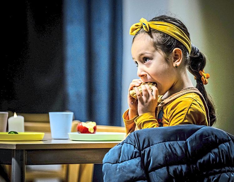 Junges Mädchen in gelber Kleidung frühstückt Gebäck