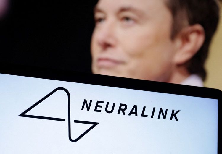 Das Bild zeigt den Schriftzug von Neuralink auf einem Smartphone-Display und ein Bild von Elon Musk im Hintergrund