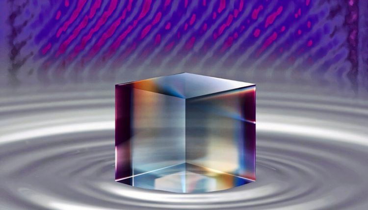Ein schimmernder, durchscheinender Würfel mit Regenbogeneffekten steht auf einer Oberfläche mit konzentrischen Wellenmustern. Im Hintergrund sind violette und blaue Lichtwellen zu sehen.