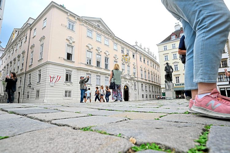 Menschen queren den Judenplatz vor dem Verwaltungsgerichtshof in Wien.