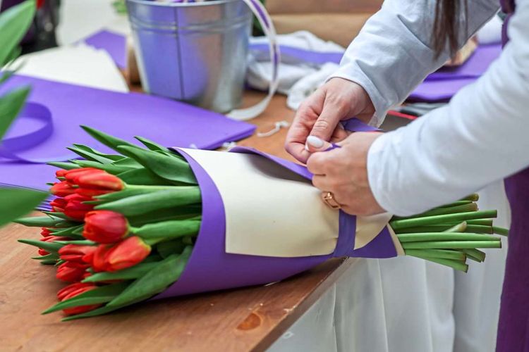 Eine Frau bindet einen Strauß Tulpen