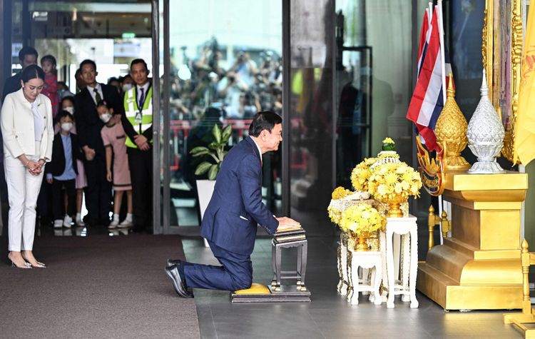 Thaksin Shinawatra kniet vor einem Altar an einem Flughafen.