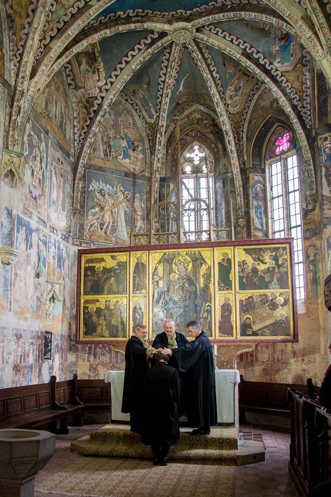Drei Männer halten in Kirche ihre Hände über den Kopf einer Pfarrerin