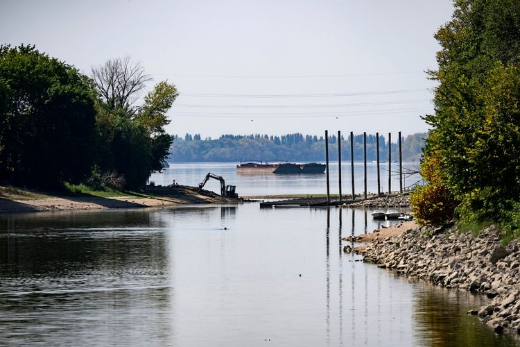 Die ausgetrockneten Ufer der Donau in Budapest, Ungarn, werden durch den extrem niedrigen Wasserstand infolge von Hitze und Dürre sichtbar. Ein Bagger steht am Ufer, mit einer Barke im Hintergrund. (Aufgenommen am 5. August 2026).