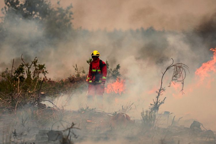 Ein Feuerwehrmann der Pariser Feuerwehr steht inmitten von Rauch und Flammen in einem Waldgebiet in Marcheprime, westlich von Bordeaux, am 26. Juli 2026. Im Hintergrund brennt die Vegetation, während der Feuerwehrmann die Lage überwacht.