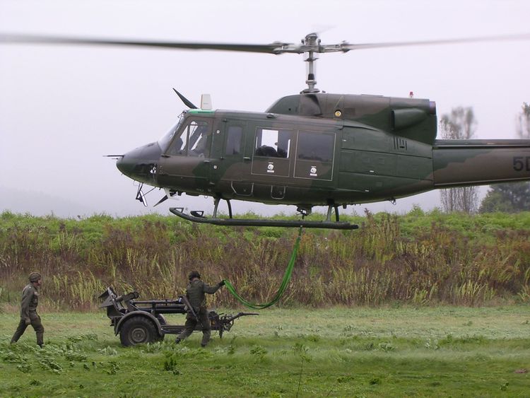 Soldaten befestigen eine Außenlast an einem Hubschrauber des Typs Bell 212
