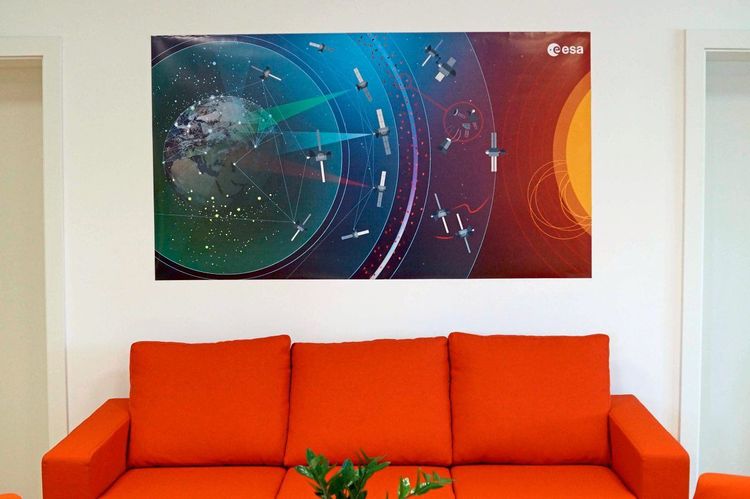 Rotes Sofa, darüber ein Poster mit Satelliten.
