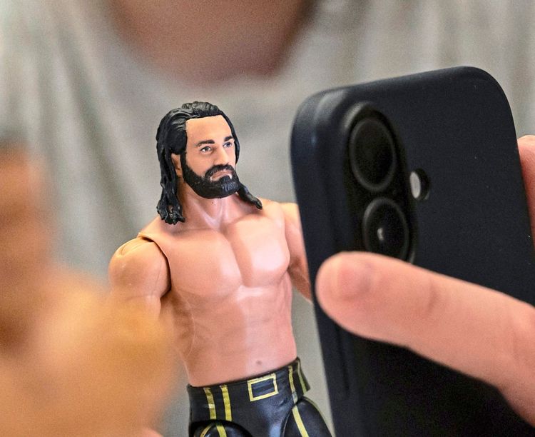 Eine Person hält eine Spielfigur aus Plastik und verwendet ein Smartphone. Die Szene spielt in einem Testlabor.