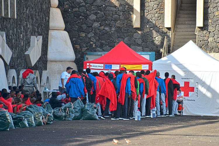 Migranten stehen vor Zelt von rotem Kreuz an