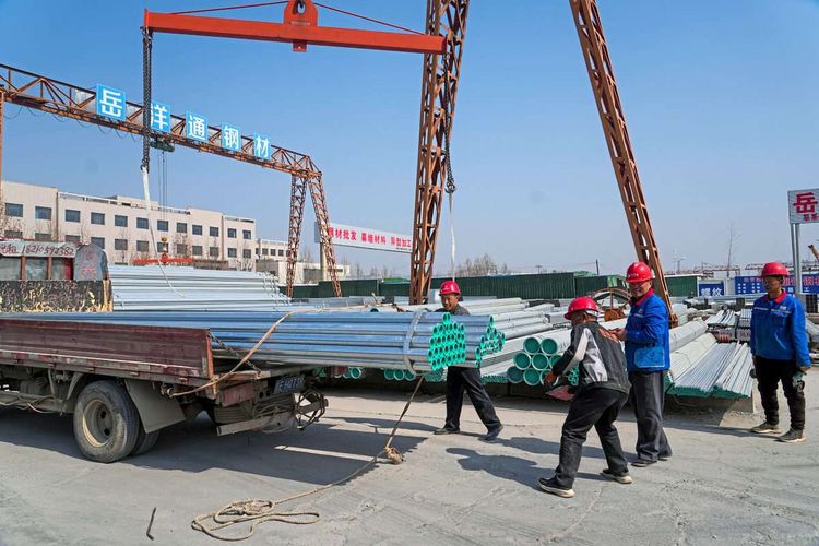 Chinesische Arbeiter laden Stahlrohre ab