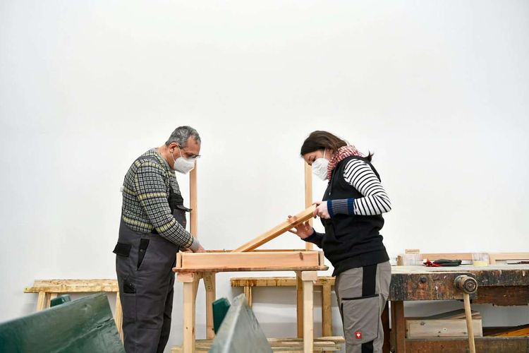 Ein Mann und eine Frau arbeiten in einer Holzwerkstatt in Marienthal an einem Möbelstück