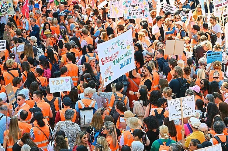 Demonstrierende Freizeitpädagoginnen und - pädagogen in Warnwesten, die Schilder in die Hand halten