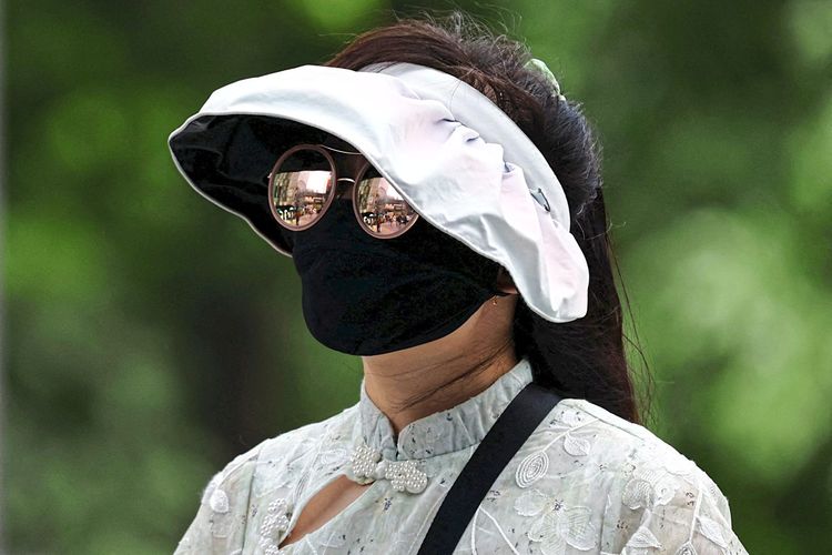 Eine Frau mit Gesichtsschutz gegen Hitze in Peking