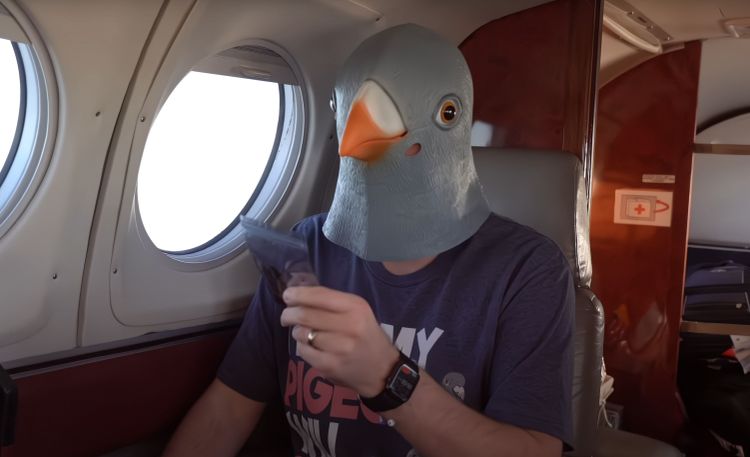 Das Bild zeigt Tech-Youtuber Jeff Geerling mit Taubenmaske in einem Flugzeug