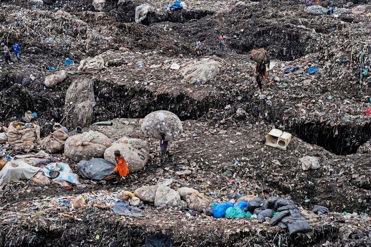 Menschen sammeln Müll auf einer Müllhalde in Kampala, Uganda, wenige Stunden nach deren teilweisem Einsturz. Die Landschaft ist von Abfallbergen und Plastiksäcken geprägt. Einige Menschen tragen schwere Säcke, während sie durch das gefährliche Gelände navigieren. Die Szene zeigt die schwierigen Arbeits- und Lebensbedingungen der Betroffenen.