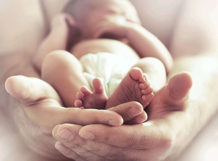Schlafendes Neugeborenes in den Händen der Mutter