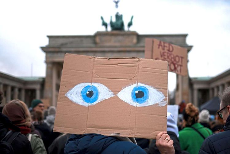 Plakat mit zwei großen Augen vor dem Brandenburger Tor