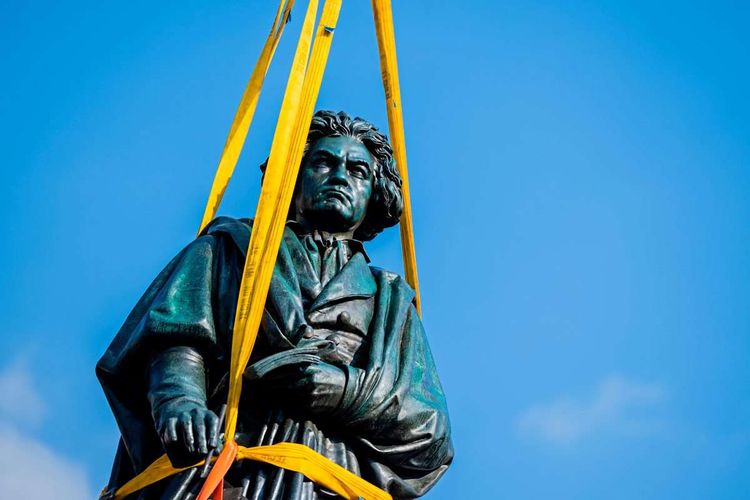 Beethoven-Statue hängt in gelben Seilen in der Luft.