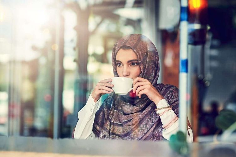 Junge muslimische Frau mit Cappuccino