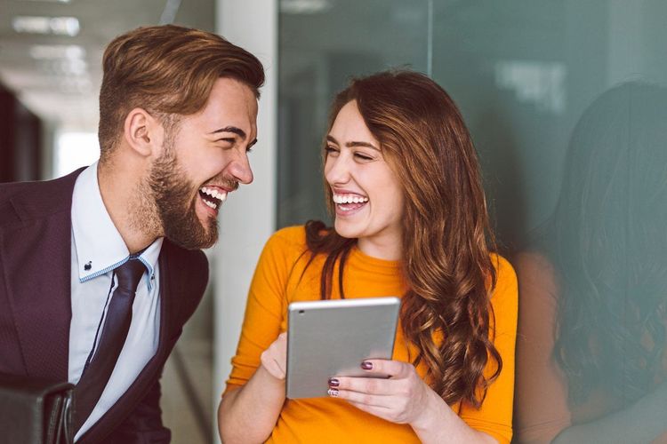 Flirt-Situation: Ein Mann und eine Frau lachen sehr vertraut zusammen im Büro