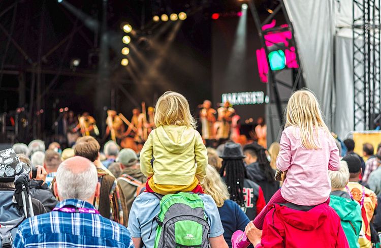 Konzertgäste von hinten mit Blick auf die Bühne, zwei Kinder auf den Schultern von Erwachsenen