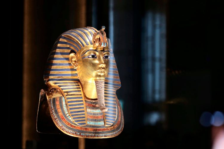 Die goldene Totenmaske von König Tutanchamun wird im Großen Ägyptischen Museum in Gizeh, Ägypten, ausgestellt. Das glänzende Artefakt, ein ikonisches Symbol des antiken Ägyptens, ist von einer dunklen und eleganten Museumsumgebung umgeben.