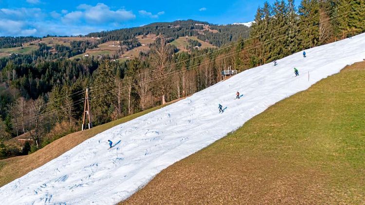 Weiße Skipiste aus Kunstschnee in grüner Landschaft