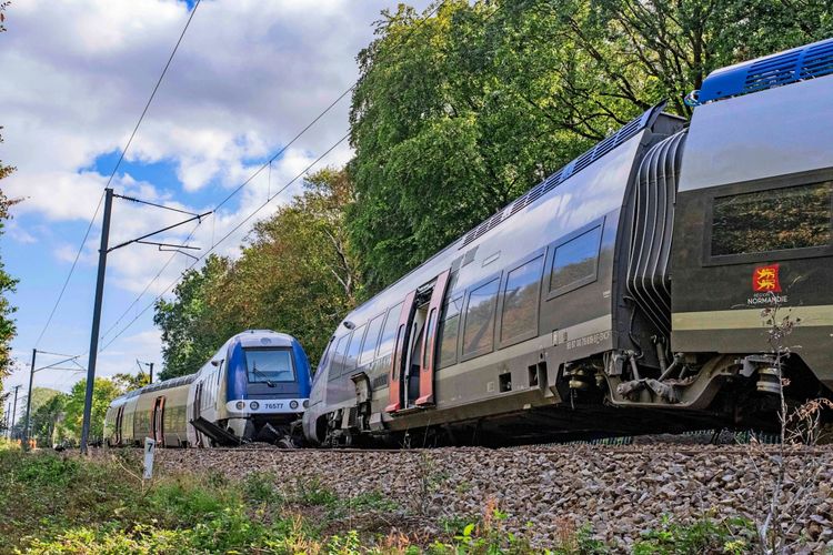 Ein entgleister SNCF TER-Zug zwischen Rouen und Caen in Cléon, Frankreich, am 12. September 2026. Der Zug befindet sich teilweise neben den Gleisen, umgeben von Bäumen und Oberleitungen.