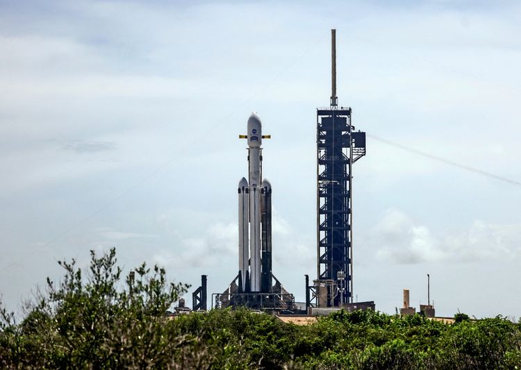 Eine SpaceX Falcon Heavy Rakete steht startbereit auf der Startrampe des Kennedy Space Centers in Cape Canaveral, Florida, USA, mit dem Nancy Grace Roman Weltraumteleskop der NASA an Bord. Aufnahme bei Tageslicht, mit Vegetation im Vordergrund und bewölktem Himmel im Hintergrund.