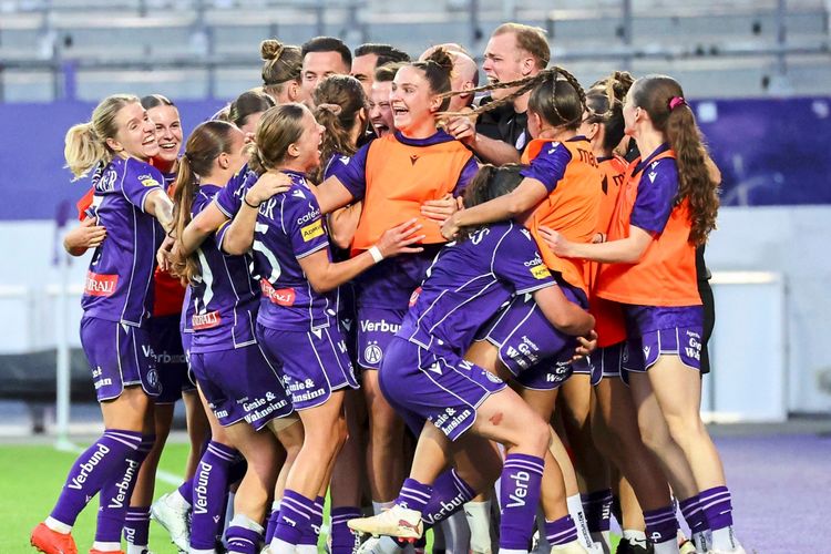 Eine Gruppe von Spielerinnen des FK Austria Wien feiert gemeinsam ein Tor während eines Fußballspiels in der Generali-Arena in Wien. Die Spielerinnen tragen lila Trikots, einige orange Überziehleibchen. Freude und Teamgeist sind deutlich sichtbar.
