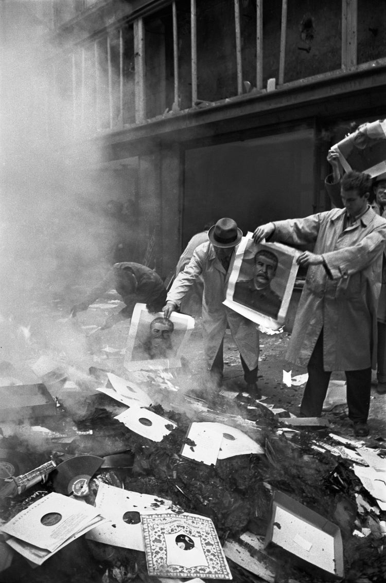 Schwarz-weißes Foto von Fotos und Dokumenten, die von Protestierenden verbrannt werden.