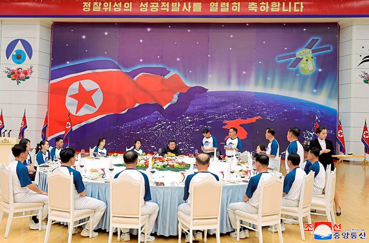 Mehrere Menschen, darunter Kim Jong-un, sitzen zusammen an einem Tisch.