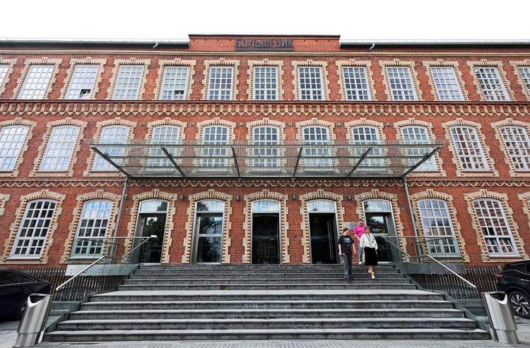 Menschen betreten ein rotes Backsteingebäude mit großen Fenstern und Glasüberdachung, das Goethe-Institut in Moskau, Russland.
