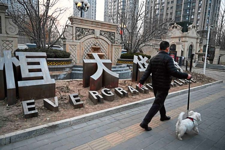 Ein Mann mit einem Hund geht an einem Wohnkomplex der Evergrande-Gruppe in Peking vorbei.