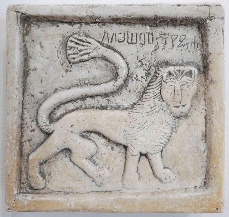 Ein Relief einer Tafel zeigt einen stilisierten venezianischen Löwen mit einer langen, geschwungenen Schwanzspitze und Inschriften in einer antiken Schrift, aus der Kirche des Heiligen Germanus auf der kroatischen Insel Brioni.