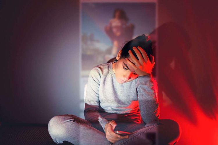 Teenager Mädchen sitzt in ihrem dunklen Zimmer und scrollt auf dem Smartphone