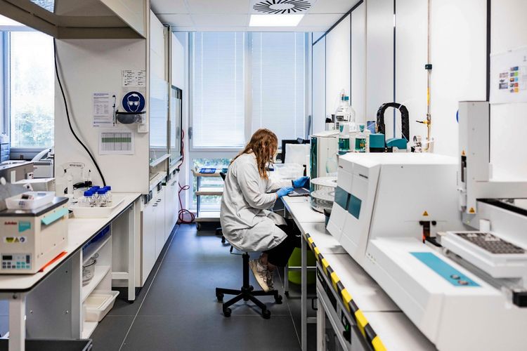 Eine Labortechnikerin arbeitet in einem Labor an der Analyse von PFAS. Das Labor ist mit moderner wissenschaftlicher Ausrüstung ausgestattet, und durch die Fenster fällt Tageslicht ein.