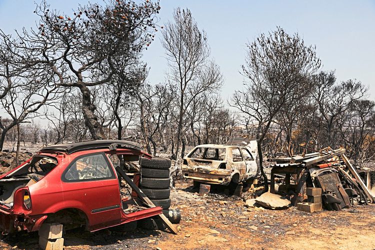 Das Bild zeigt zwei ausgebrannte Autos in Mandra, Griechenland.
