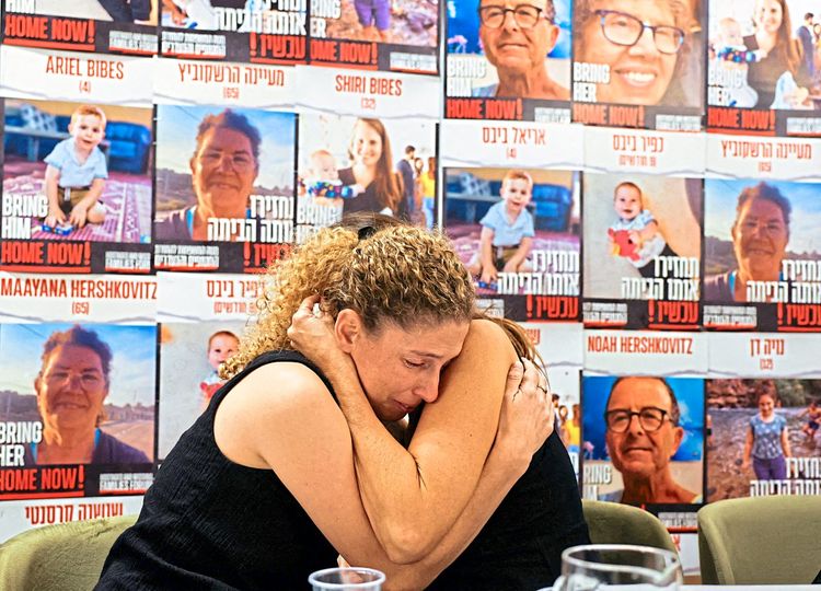 Adva Gutman-Tirosh und Lee Dan trösten einander vor einer Wand mit Postern von Vermissten.