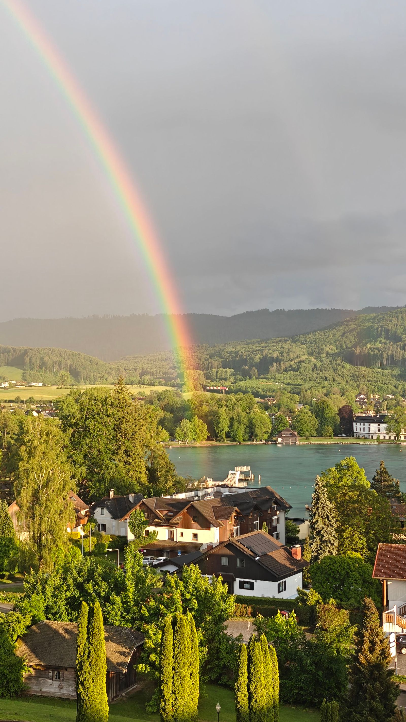Ein Regenbogen erhebt sich Häusern und einem See.