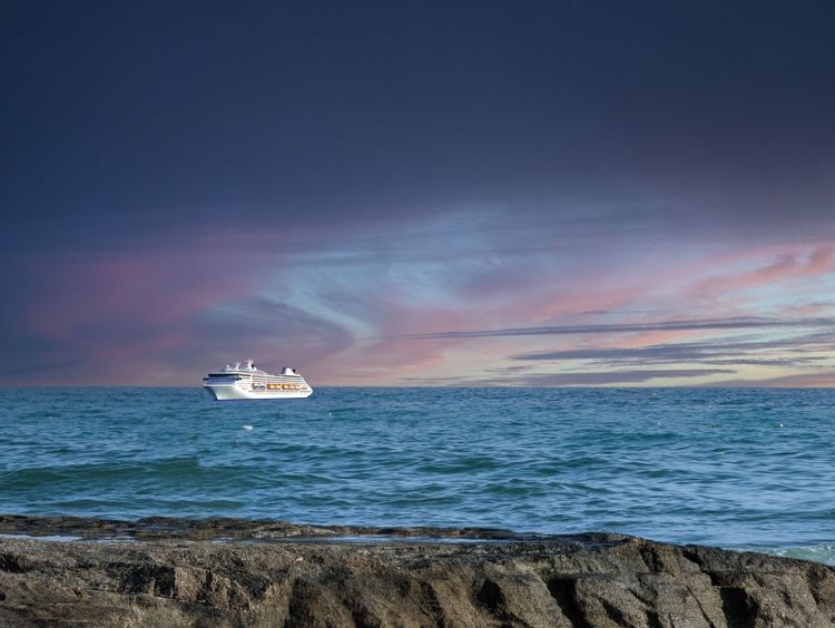 Bild von einem Strand mit einem Kureuzfahrtschiff.